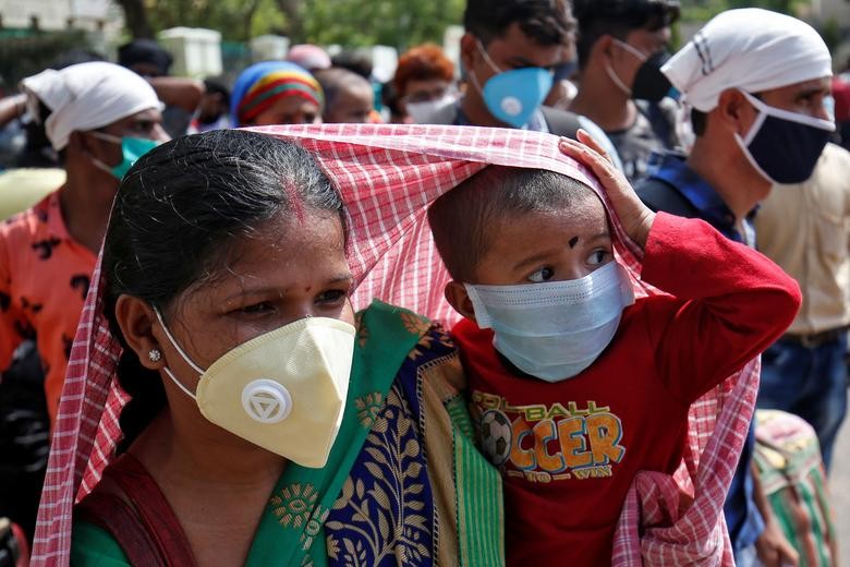 A migrant worker covers her child with a scarf to protect it from the heat, as they wait to get on a bus for a railway station, where they will board a train to their home state of West Bengal, after some restrictions were lifted during an extended nationwide lockdown to slow the spread of the coronavirus disease (COVID-19), in Ahmedabad, India, June 5, 2020. REUTERS/Amit Dave